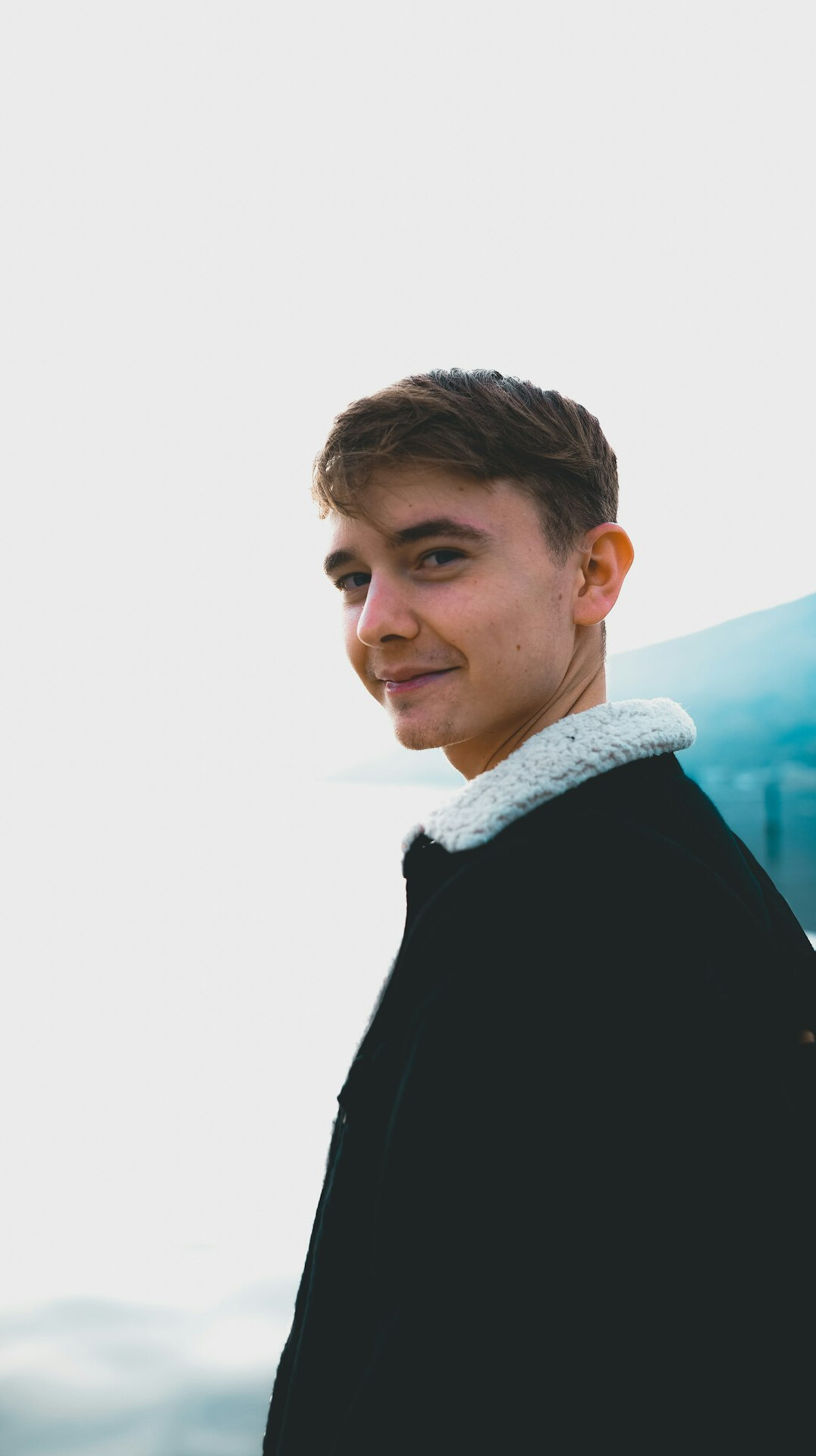 Portrait of a smiling man in a dark jacket against a neutral background